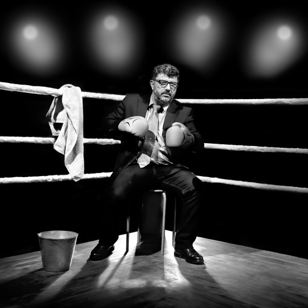 un homme assis dans le coin d'un ring de boxe, gants en mains